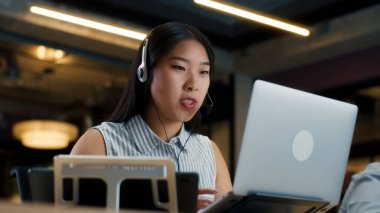 Bilgisayarı ve dijital tableti kullanarak müşteriyle çevrimiçi konuşan Asyalı kadın operatör. Pazarlama şirketinin çağrı merkezinde çalışıyorum.