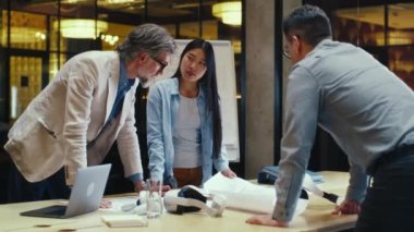 Çok ırklı mühendisler evrak ve planlara bakıyorlar, iş stratejilerini tartışıyorlar, mühendislik projesi üzerinde çalışıyorlar. Ofis konferans odasında iş toplantısı.