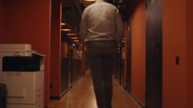 Koridorda elektrikli scooter süren, erkek arkadaşla buluşan ve selamlaşan bir adamın arka görüntüsü. Pazarlama şirketi koridoru.