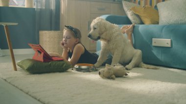 Genç kız film seyrediyor, yastığa sarılıyor, köpek uyuyor ve hafif bir halıda rüya seyrediyor, boş zamanlarını evde birlikte geçiriyorlar. Golden retriever.