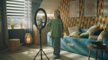 Kız telefonda kaydı açıyor, mobil uygulamalarda sosyal ağ için içerik yaratıyor, dans ediyor ve şarkı söylüyor, eğlenceli takipçiler, kişisel kanalı zorluyor, moda videosu yaratıyor.