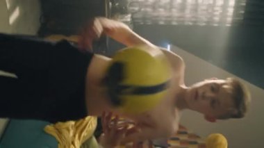 Genç futbolcunun dikey video çekimi dizleriyle oyunlar oynayarak futbol topunu kontrol ediyor. Üstsüz genç çocuk spor yapıyor. Futbol hayranıyım. Okul sporu takımı oyuncusu.