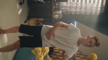 Hevesli bir çocuğun yatak odasında futbol oynarken çekilmiş dikey videosu. Maçtan önce genç bir futbolcu. Spor takımının futbolcusu içeride spor yapıyor. Sağlıklı yaşam tarzı.