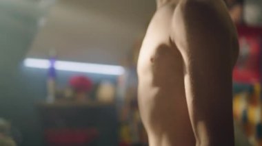 Genç kaslı çocuk odasında halterli kıvrımlar yapıyor. Pazularına ve kaslı kaslarına yakın çekim. Aynada kaslarını kontrol ediyor. Ağırlık çalışması, fitness, fiziksel aktivite. Sağlıklı yaşam tarzı kavramı.