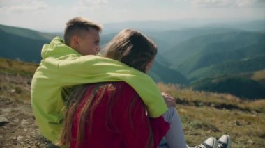 Genç adam ve genç kız Stone Hill 'de birlikte oturuyorlar. Birkaç arkadaş güzel doğa manzarasını seyrediyor, gülümsüyor ve mutlu hissediyorlar, boş zamanlarını dışarıda geçiriyorlar. Arka plan görünümü.