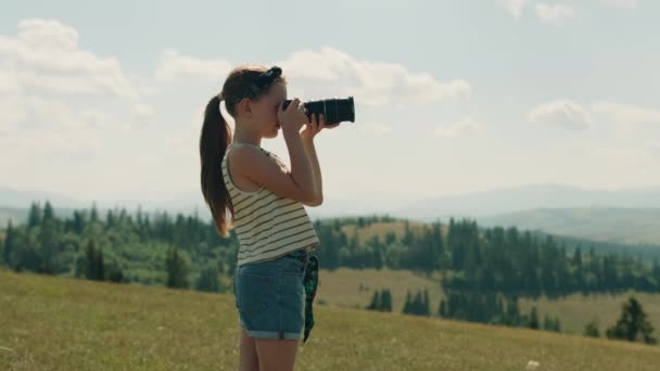 年轻的摄影师在美丽的绿色山路上拍摄风景 拍摄大自然的照片 女孩在包里塞满了令人惊奇的照片 在户外消磨时光 — 图库视频影像