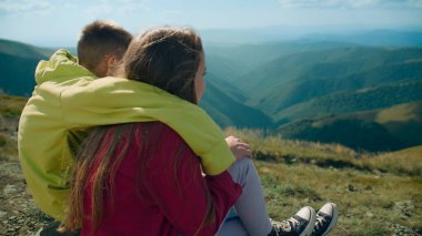 Genç adam ve genç kız Stone Hill 'de birlikte oturuyorlar. Birkaç arkadaş güzel doğa manzarasını seyrediyor, gülümsüyor ve mutlu hissediyorlar, boş zamanlarını dışarıda geçiriyorlar. Arka plan görünümü.