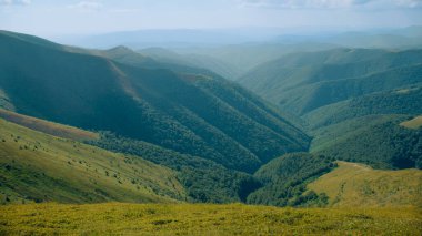 Dağlar arasındaki güzel tepelerin vadisinin manzarası. Temiz doğanın estetik manzarası, taze sisli hava. Yüksek kayadan inanılmaz manzara