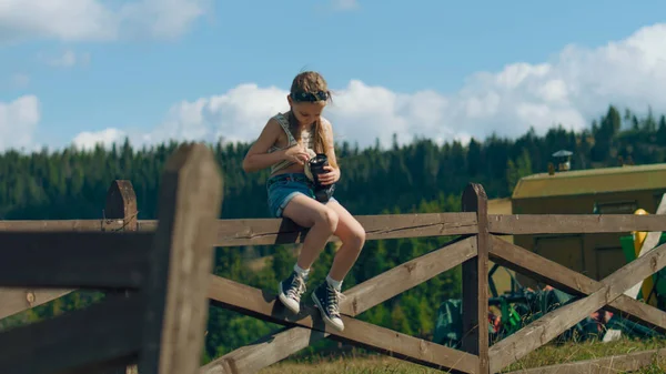 Młody Fotograf Wycierający Obiektyw Aparatu Cyfrowego Koszulką Siedzący Drewnianym Ogrodzeniu — Zdjęcie stockowe