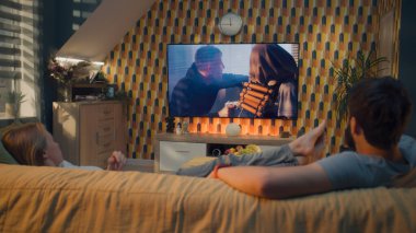 Bir çift, rahat bir oturma odasında kanepede oturup, aksiyon filmi seyrediyor ya da TV 'de kriminal blockbuster izliyor, boş zamanlarında evde takılıyor. Modern dairede ev sineması.