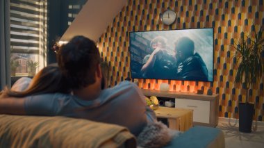 Oturma odasındaki kanepede oturan çift, TV 'de aksiyon filmi izliyor ya da canlı yayında kriminal blockbuster izliyor, konuşuyor ve oyunculuğu tartışıyor, hafta sonları evde dinleniyor. Modern dairede ev sineması.
