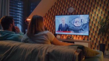 Kanepede oturan çift oturma odasında aperatiflerle, TV kanalında astronotlar, uzay görevi, Dünya yörüngesini keşfetmek hakkında haberler izliyorlar. Karı koca dinleniyor ve hafta sonları evde dinleniyor.