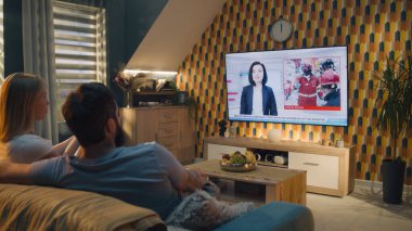 Oturma odasındaki kanepede oturan çift, sohbet ediyor, TV haberleri seyrediyor, terör saldırısı, bina çökmüş ve insanları enkazdan kurtarıyor. Evde vakit geçirmek. TV canlı