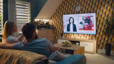 Oturma odasındaki kanepede oturan çift, sohbet ediyor, TV haberleri seyrediyor, terör saldırısı, bina çökmüş ve insanları enkazdan kurtarıyor. Evde vakit geçirmek. TV canlı