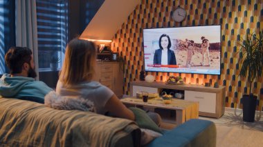 Kanepede oturan çift oturma odasında aperatiflerle, TV kanalında astronotlar, uzay görevi, Mars 'ı keşfetmek hakkında haberler izliyorlar. Erkek ve kadın hafta sonları evde dinleniyorlar..