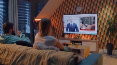 Oturma odasındaki koltukta oturan çift, askeri tatbikatlar, NATO eğitimi, silahlı kuvvetler hakkında TV haberleri izliyor. Kadın ve erkek geceyi evde geçiriyorlar. TV canlı yayın.