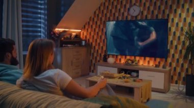 Mutlu çift kanepede oturuyor, TV 'de aksiyon filmi izliyor ya da canlı yayında kriminal blockbuster izliyor, konuşuyor ve oyunculuğu tartışıyor, abur cubur yiyor, pizza yiyor, cips yiyor. Akşamları evde dinlenen eşler.