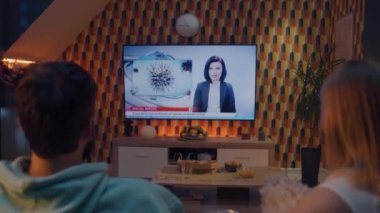 Oturma odasındaki kanepede oturup birbirlerine bakıyorlar, çocuk felci ve su kirliliği hakkında TV haberleri izliyorlar. Kadın ve erkek geceyi evde birlikte geçiriyorlar. TV canlı yayını.