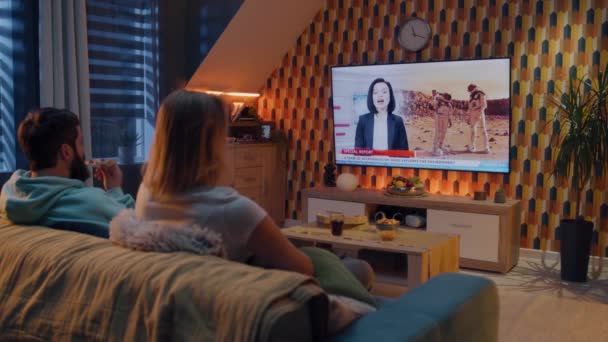 Pasangan Duduk Sofa Dengan Makanan Ringan Ruang Tamu Menonton Berita — Stok Video