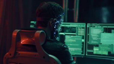 Fütüristik kulaklık takan, LED ışıkları olan esmer bir adamın arka planı programlara bağlanmış ve çoklu bilgisayar ekranı kullanarak kod geliştiriyor. Cyperpunk tarzı. Bilim kurgu geçmişi. Neon ışıkları.