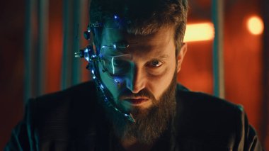 Siyah deri ceketli sakallı genç adam kameraya şiddetle bakıyor. Tek gözlü gözlüklü ve kulaklıklı adam kaçmasın diye siyah çubukların arkasında asılı kalmış..