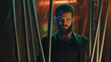 Siberpunk tarzı esmer genç adam siyah çubukların arkasında asılı duruyor. Fütürist bir kulaklık takmış, göz merceği ve mikrofon takmış. Neon ışıkları arka planda. Bilim kurgu.
