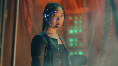 Siyah deri ceketli siber punk kız kameraya şiddetle bakıyor. Tek gözlü ve kulaklık takmış Asyalı bir kız. Kaçmasın diye siyah kalın çubuklar asılmış..