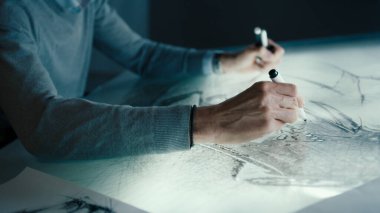 Üst düzey bir otomotiv tasarımcısının elleri, yüksek teknolojili yenilikçi bir laboratuvarda kalem kullanarak dijital ekran grafikleriyle çalışırlar. Bir prototip modelinin taslağını çizer