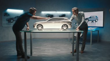 Deneyimli araba tasarımcıları ve geliştiriciler, yüksek teknoloji otomobil üretim şirketinde kilden yapılmış prototip model arabanın tasarımı ve şeklini tartışırlar..