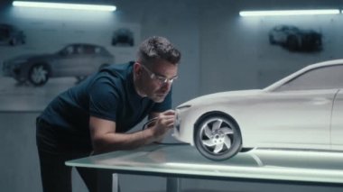 Kıdemli otomotiv tasarım mühendisi yüksek teknoloji şirketinde bir araba modelinin tırmık heykelini mükemmelleştirmek için döner bir araç kullanır. Güvenlik gözlüğü takan mühendis bir otomotiv şirketinde çalışıyor..