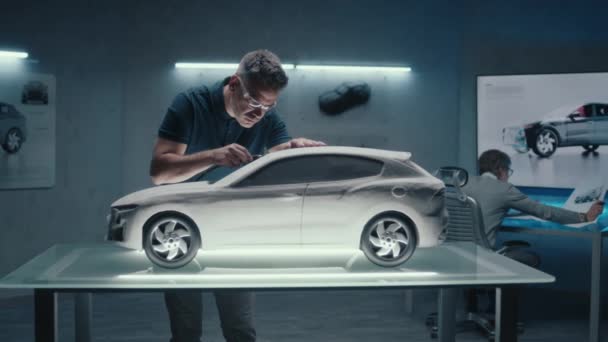上級自動車技術者はハイテク自動車製造会社で働いています 1台は試作車の彫刻を もう1台はデジタルタッチスクリーンテーブルを使ってスケッチを描く — ストック動画
