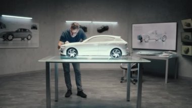 Bir otomotiv mühendisi ve tasarımcısı modern bir stüdyoda bir otomotiv şirketinin parlak LED 'ine sahip prototip model bir araba üzerinde çalışıyor. Tasarım Düzeltmeleri Yapılıyor.