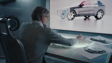 Otomotiv tasarımcısı, yüksek teknolojili yenilikçi bir laboratuvarda stilus kalem kullanarak dijital ekran grafikli bir arabanın prototip modelini çizer..