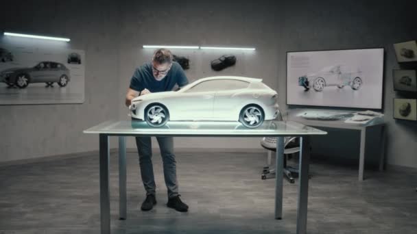 一位汽车工程师和设计师在一间拥有一家汽车公司明亮Led的现代工作室里工作的样车模型 作出设计更正 — 图库视频影像