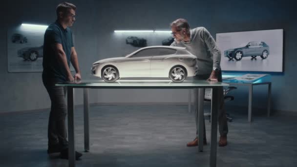 経験豊富な自動車設計者と開発者は ハイテク車製造会社で粘土で作られたプロトタイプモデル車の設計と形状について話し合います — ストック動画
