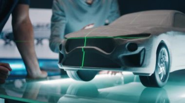 Kıdemli otomotiv mühendisleri, bir heykel prototip araba modelinin önünde mükemmellik için yeşil lazer ışığını kullanarak araba tasarımını tartışıyor. Yüksek teknoloji laboratuarında cam bir masaya yerleştirilmiş model bir araba..