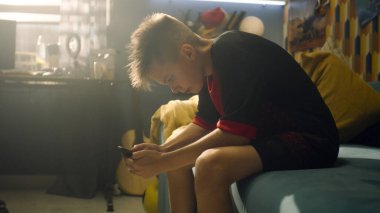 Öğrenci kanepede oturur ve telefonunu kullanır. Sırt çantasını halıdan aldı ve arkadaşlarıyla buluşmaya gitti. Gençlik, okul hayatı konsepti.