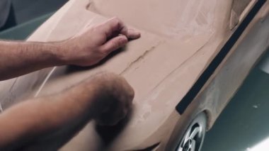 Erkek otomotiv tasarımcısının plastik kilden fütüristik araba modeli yarattığı yüksek açılı bir çekim. Yeni nesil elektrikli arabanın gelecekteki tasarımı. Modern araba tasarım stüdyosunda çalışıyorum..