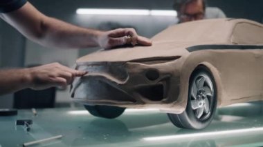 İki erkek otomotiv tasarımcısı, tırmık ve diğer aletlerle çevre dostu arabanın fütüristik plasticine kil modelini yaratıyor. Yeni nesil elektrikli arabanın gelecekteki tasarımı. Modern araba tasarım stüdyosunda çalışıyorum.