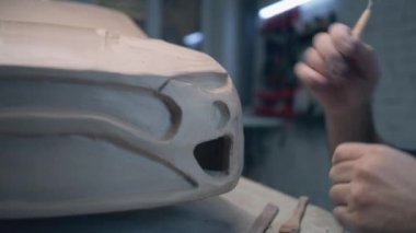 Deneyimli araba tasarımcısı, tasarımda detaylar için kil oyma kablo döngüsü aracı kullanarak arabanın prototip modeli üzerinde çalışır. El yapımı araba heykeli ham çamurdan yapılmıştır..