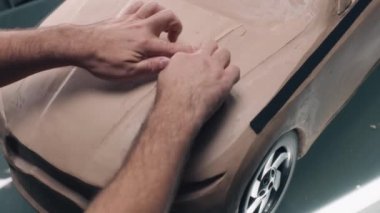 Erkek otomotiv tasarımcısının plastik kilden fütüristik araba modeli şekillendirdiği yüksek açılı bir çekim. Yeni nesil elektrikli arabanın gelecekteki tasarımı. Modern araba tasarım stüdyosunda çalışıyorum..
