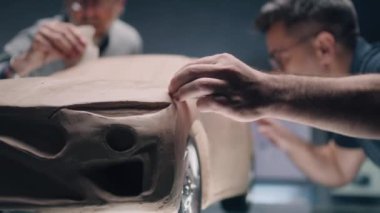 İki erkek otomotiv tasarımcısı profesyonel aletlerle arabanın fütüristik plastik kil prototipini oluşturuyorlar. Yeni nesil elektrikli arabanın gelecekteki tasarımı. Modern araba tasarım stüdyosunda çalışıyorum..