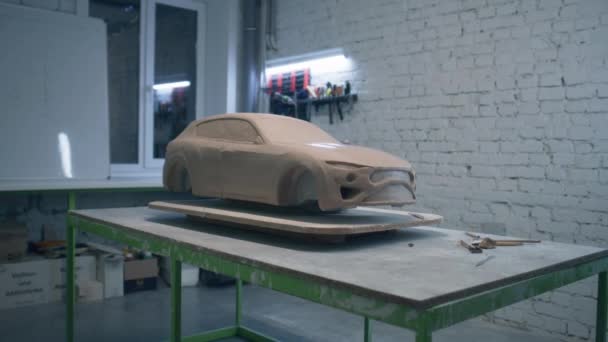 木製のテーブルの上に置かれた環境に優しい車のプロトタイプの彫刻は 彫刻ツールを敷設ワークショップで 試作車の未完成の彫刻 — ストック動画