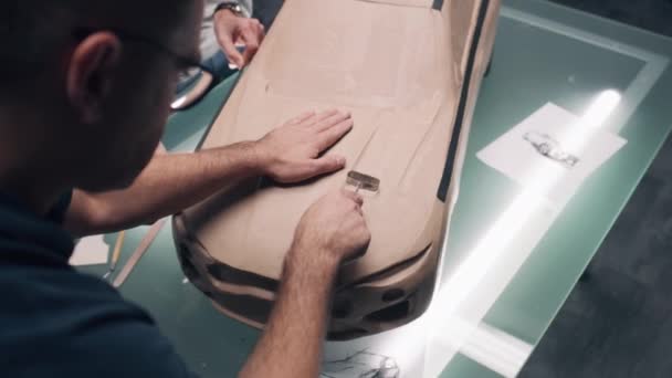 两名男性汽车设计师用耙雕刻汽车未来塑性塑料黏土模型 新一代电动汽车的未来设计 在现代汽车设计工作室工作 — 图库视频影像