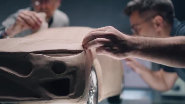 2人の男性の自動車設計者は プロのツールを使用して車の未来的なプラスチック粘土プロトタイプを作成します 新世代電気自動車の将来設計 現代のカーデザインスタジオで働く — ストック動画
