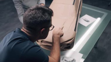 İki erkek otomotiv tasarımcısının özel aletlerle çevre dostu plasticine kil araba modeli üzerinde çalışırken yüksek açılı çekimi. Yeni nesil elektrikli arabanın gelecekteki tasarımı. Modern araba tasarım stüdyosunda çalışıyorum.