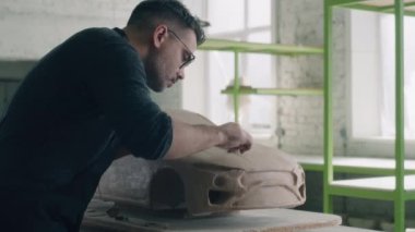 Son sınıf araba tasarımcısı elektrikli araba modeli prototipi yapıyor. Tasarım detayları ve pürüzsüz yüzey için kilden parçalar oluşturmak için kablo döngüsü aracı kullanır. Otomotiv endüstrisi.