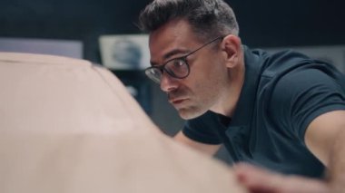 Erkek orta yaşlı otomotiv tasarımcısı plasticine kil modelinde çalışıyor. Yeni nesil elektrikli arabanın gelecekteki tasarımı. Modern araba tasarım stüdyosunda çalışıyorum..