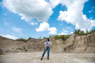 Günlük kıyafetli genç bayan yaz vakti kum kayalıklarında rahatla.