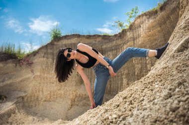 Gündelik giysiler içinde genç ve güzel bir bayan kum ocağında dinleniyor, tatilde ve yaz tatilinde seyahat ediyor.
